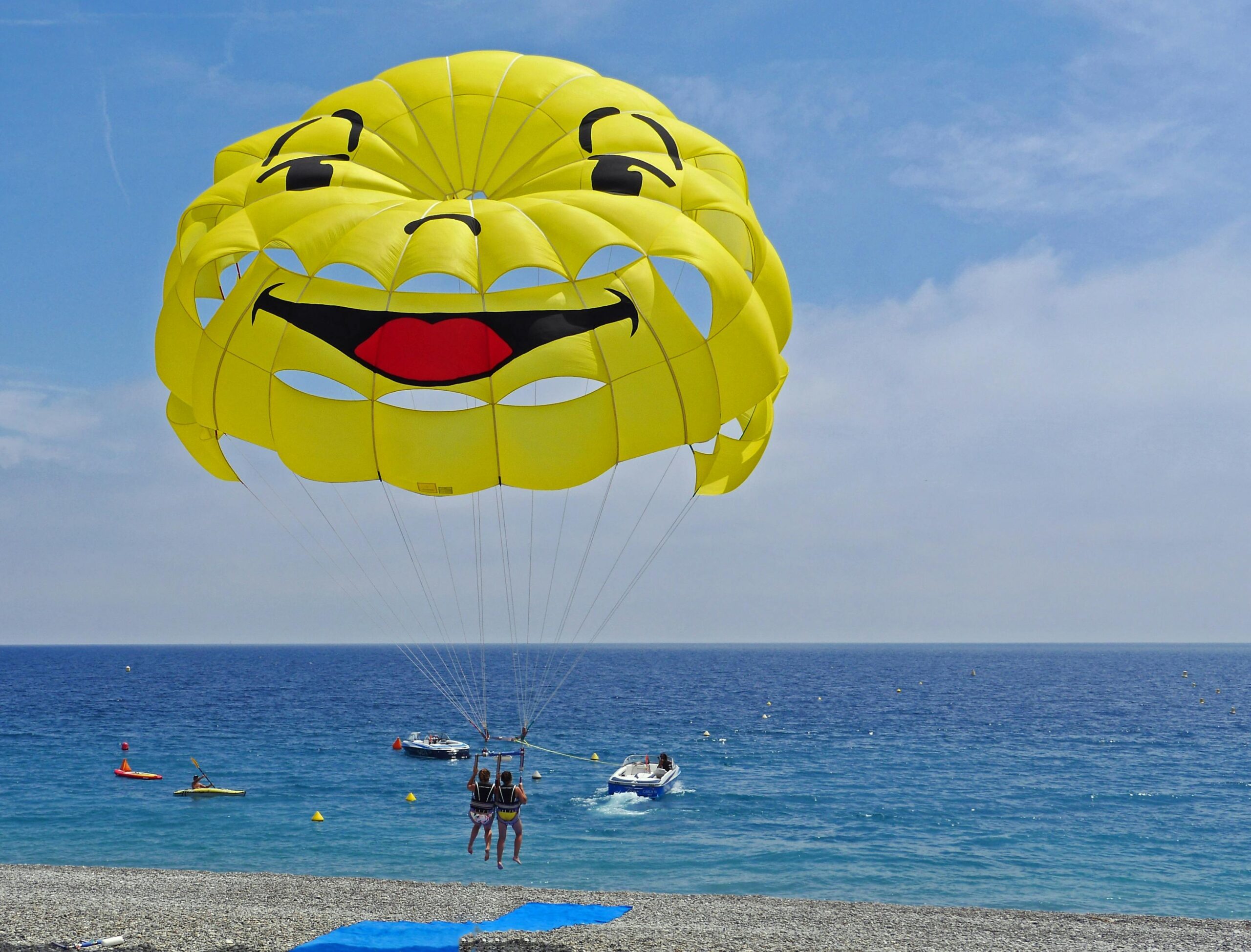 Parasailing over vibrant blue waters with a smiley face parachute, capturing summer fun and adventure.