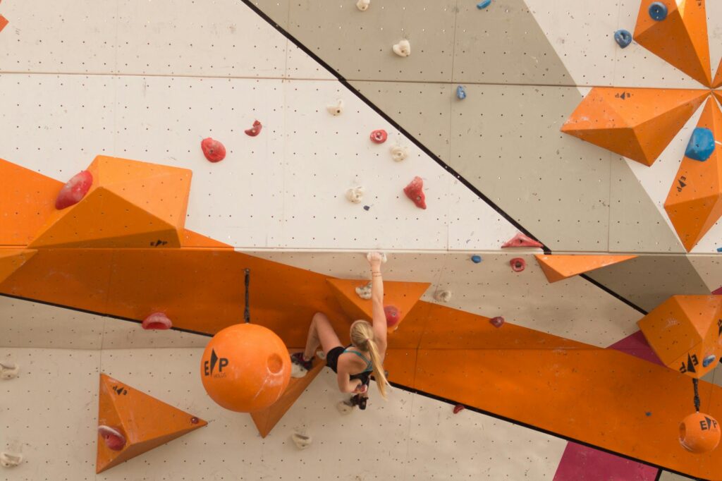 An athlete boulders on a vibrant indoor climbing wall.