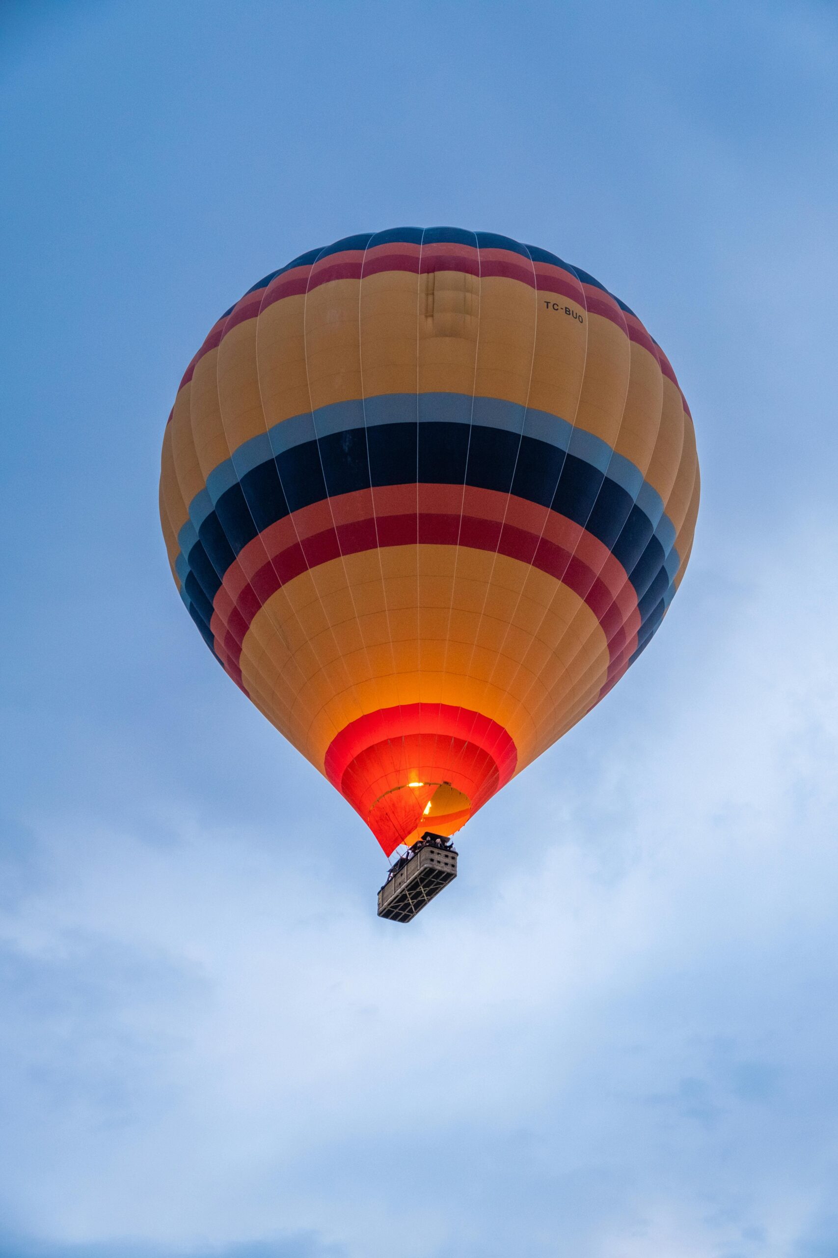 A vibrant hot air balloon floats against a clear blue sky in Cappadocia, Turkey.