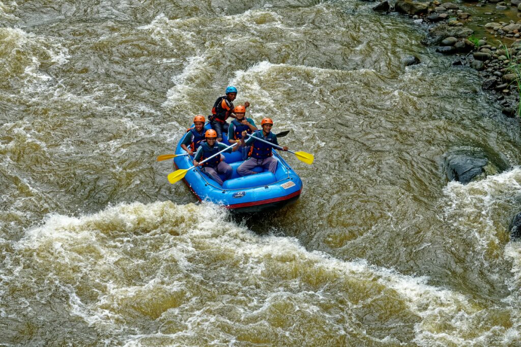 Group of adults rafting in Cikidang, West Java, showcasing teamwork on rough waters.