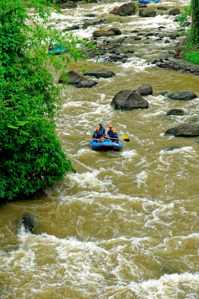 Experience thrilling rafting on a rocky river in lush West Java landscape.