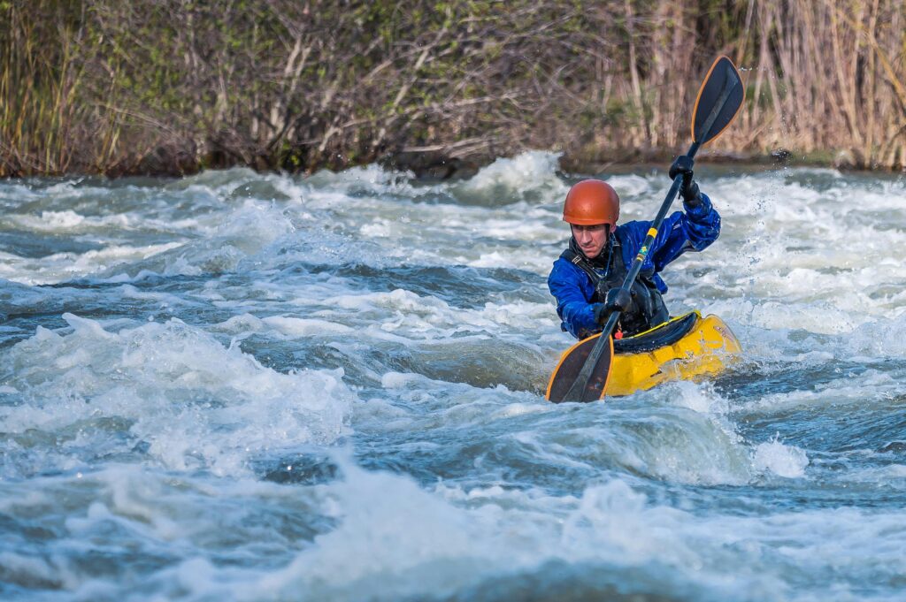 A kayaker skillfully navigates wild rapids in an exhilarating outdoor whitewater adventure.