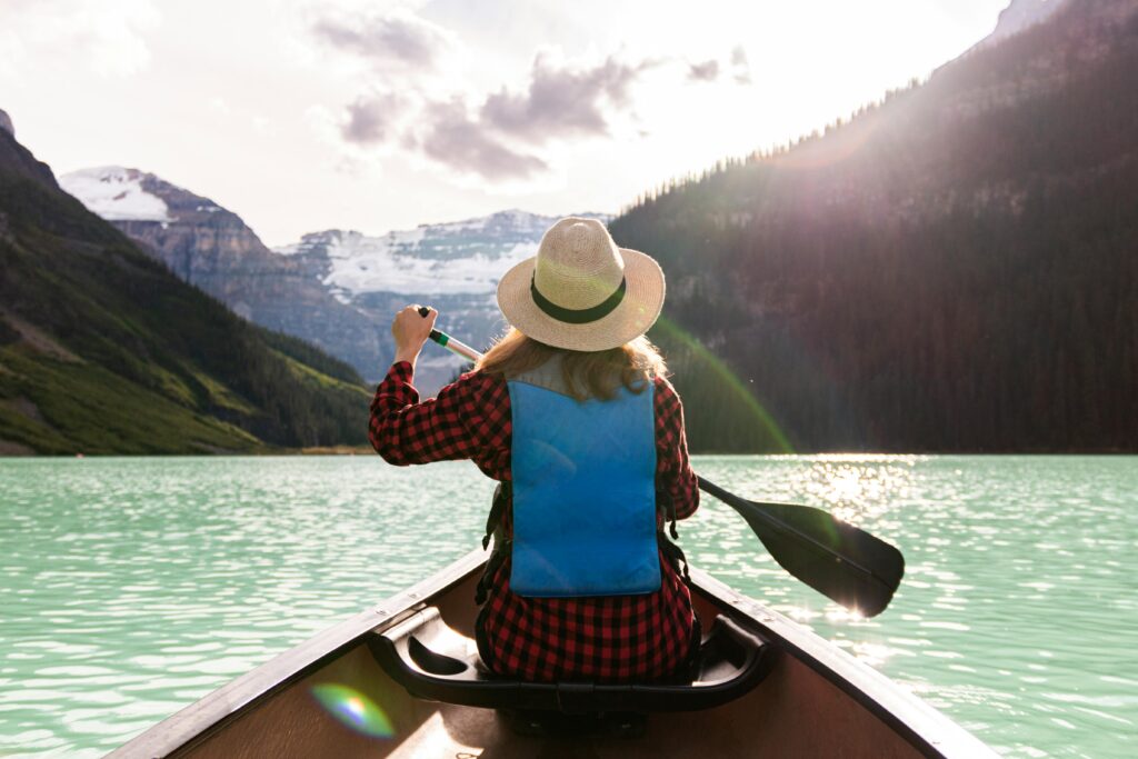 Woman paddles canoe in Lake Louise, enjoying a peaceful summer adventure.