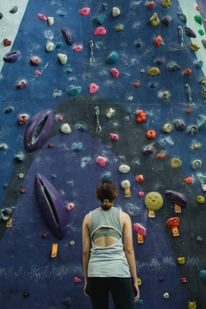 Focused woman in activewear facing an indoor climbing wall, preparing for ascent.