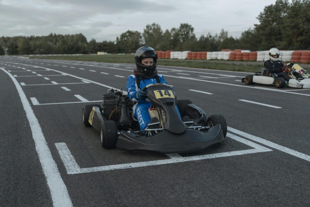 A go-kart racer ready at the starting line on an outdoor racing track during daytime.