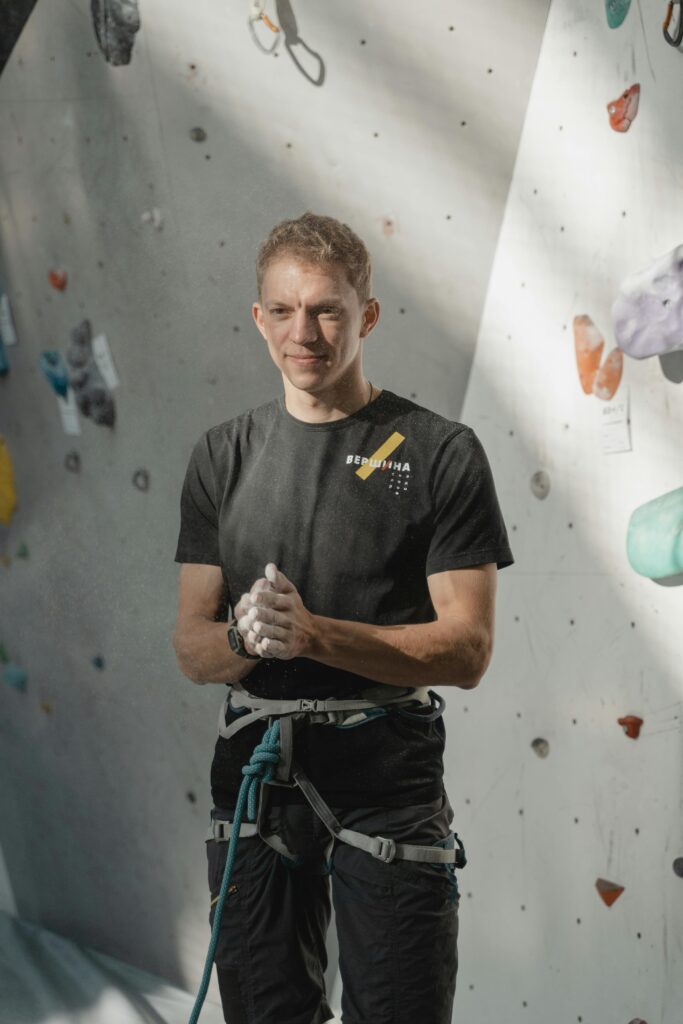 Man in climbing gear prepping for indoor rock climbing challenge.