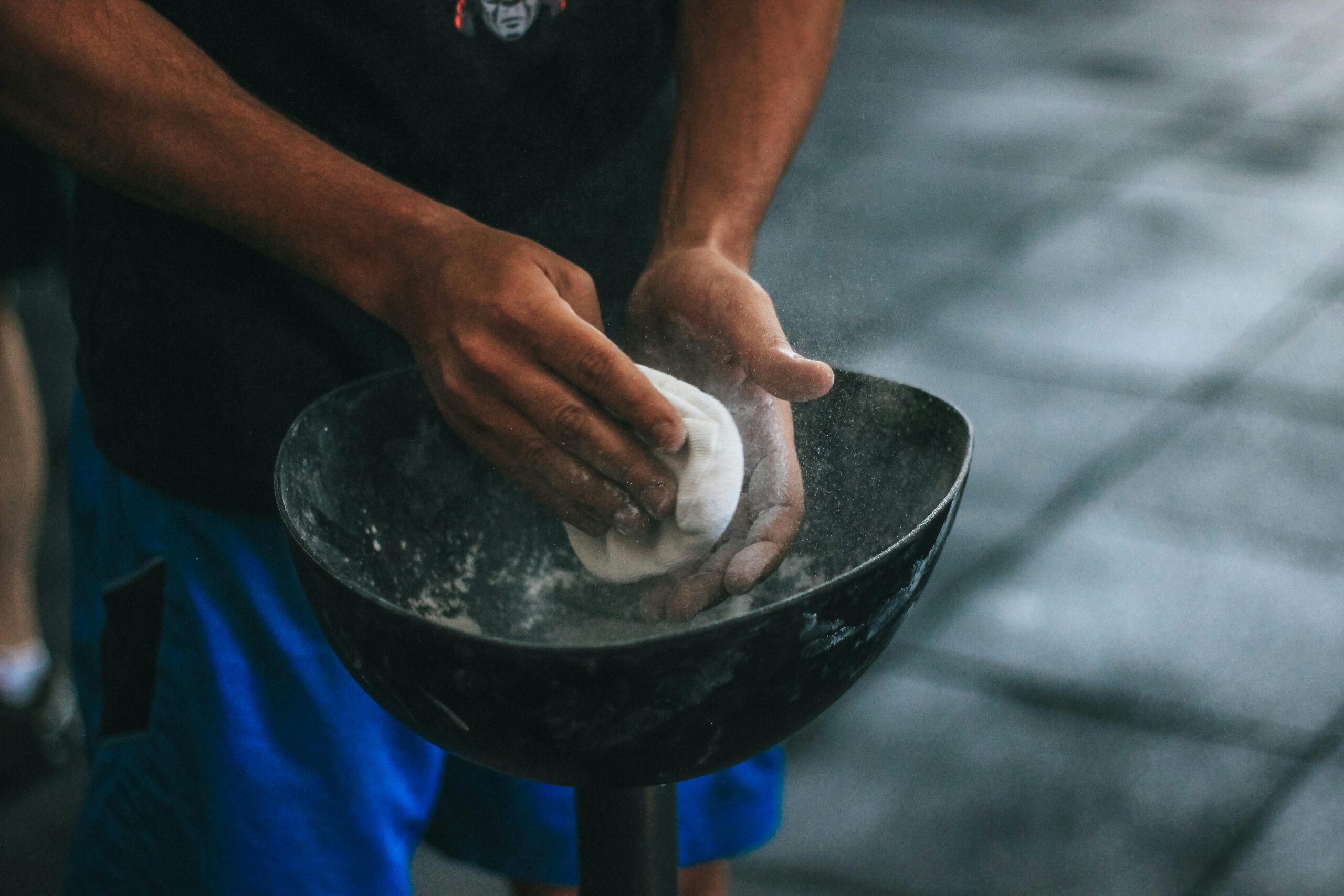 A man prepares chalk powder for climbing exercises with focus on hands in motion.