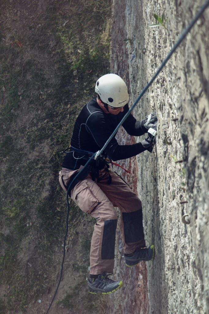 Adult man rock climbing outdoors with helmet and gear