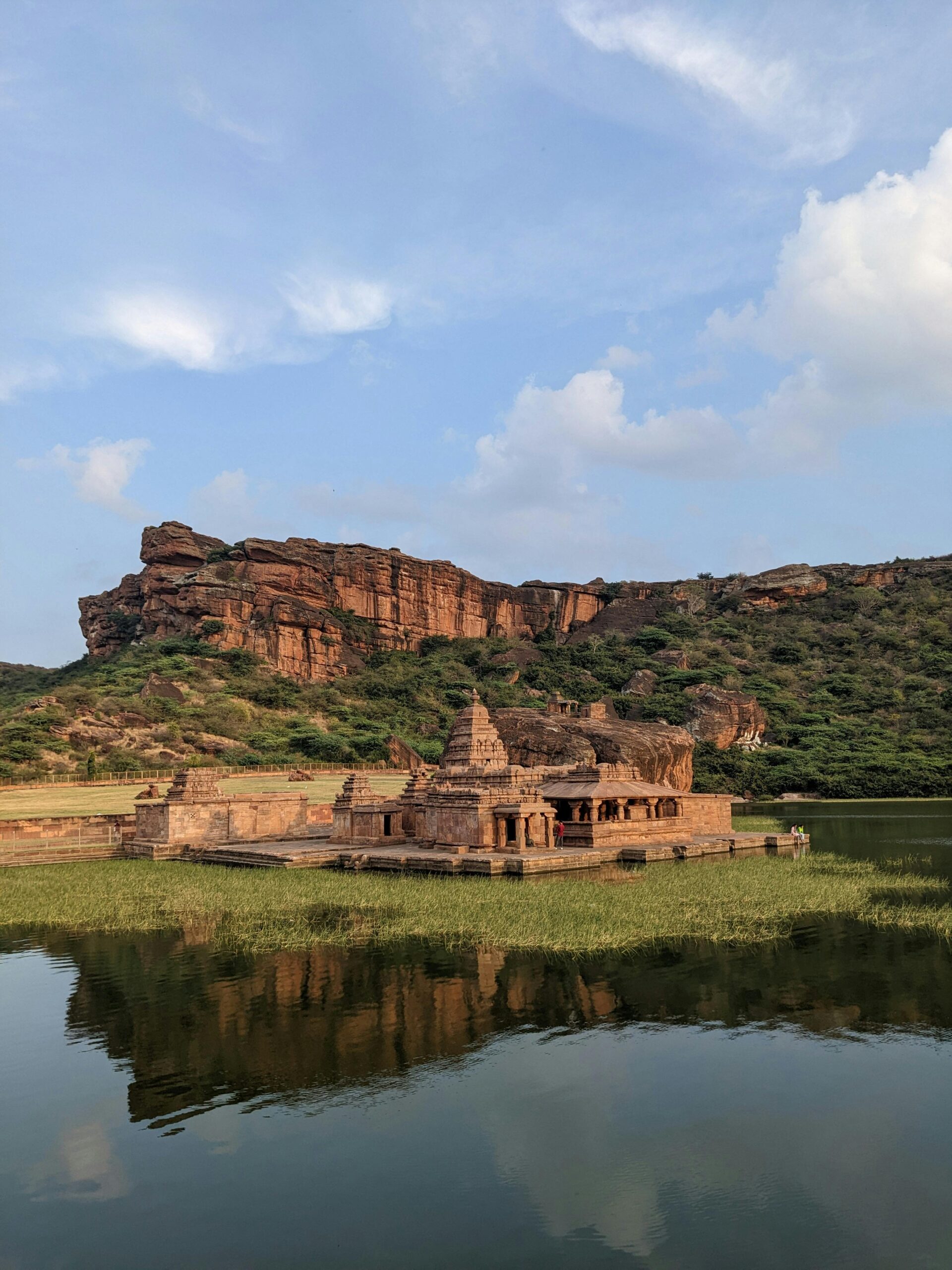 Beautiful view of the Badami rock cut temple with reflections on the lake, under a clear sky.